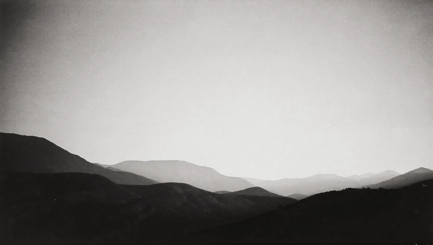 Black and white photograph of the Wasatch mountain ridgeline receding into haze