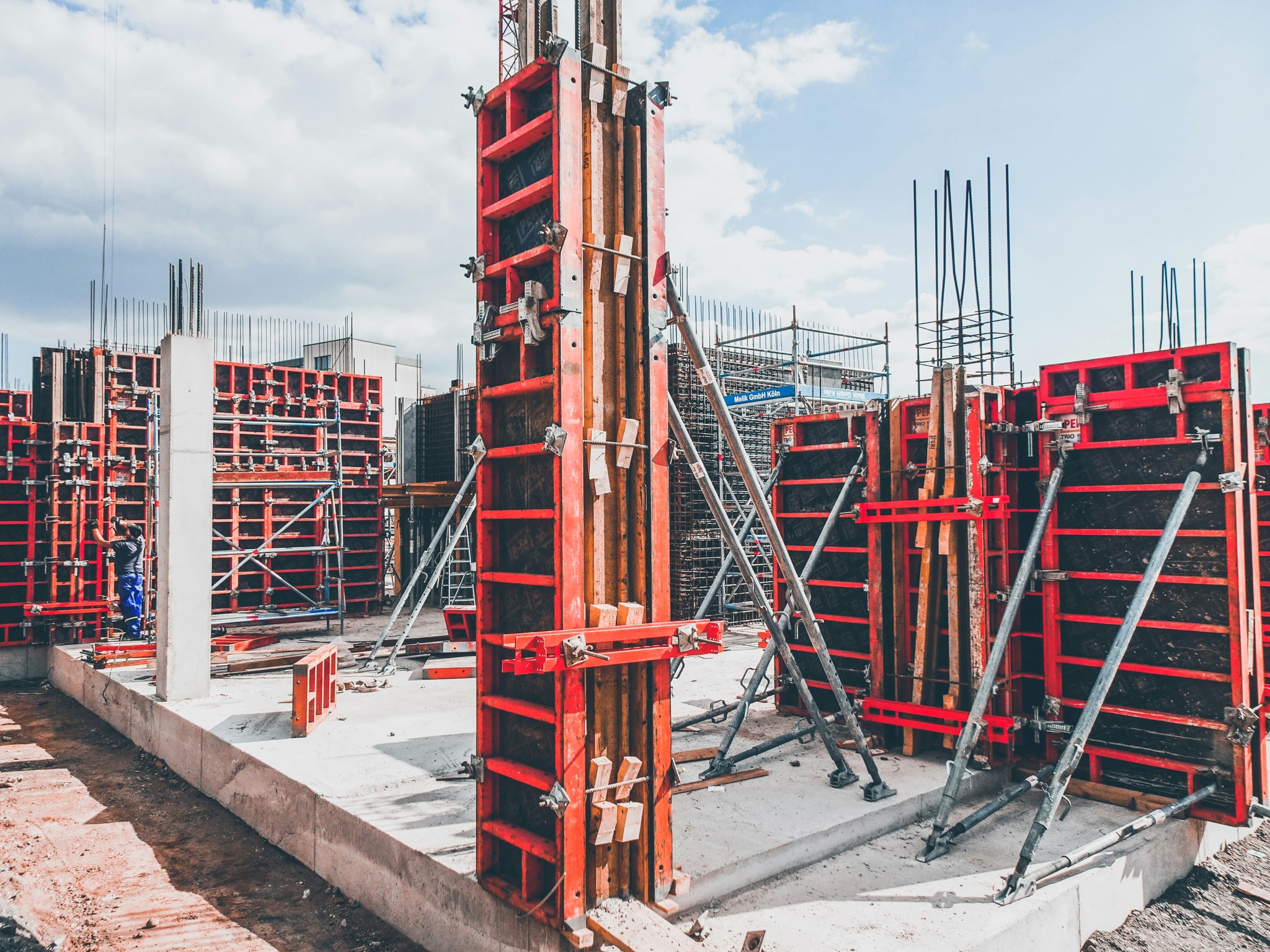 A construction site framed in red formwork against a blue sky