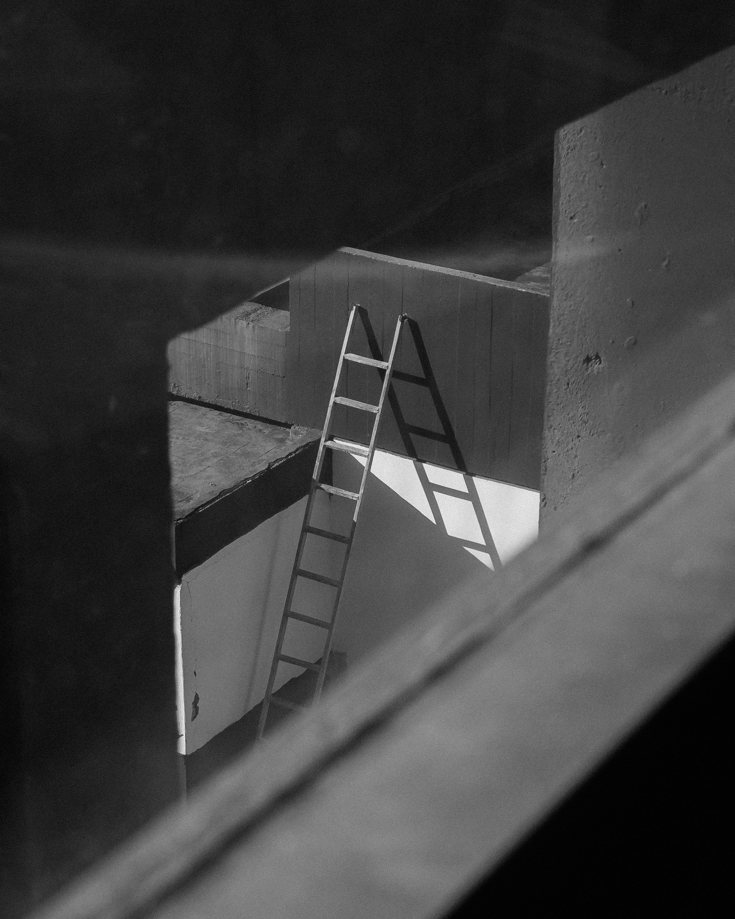 A ladder casting a long geometric shadow across a wall
