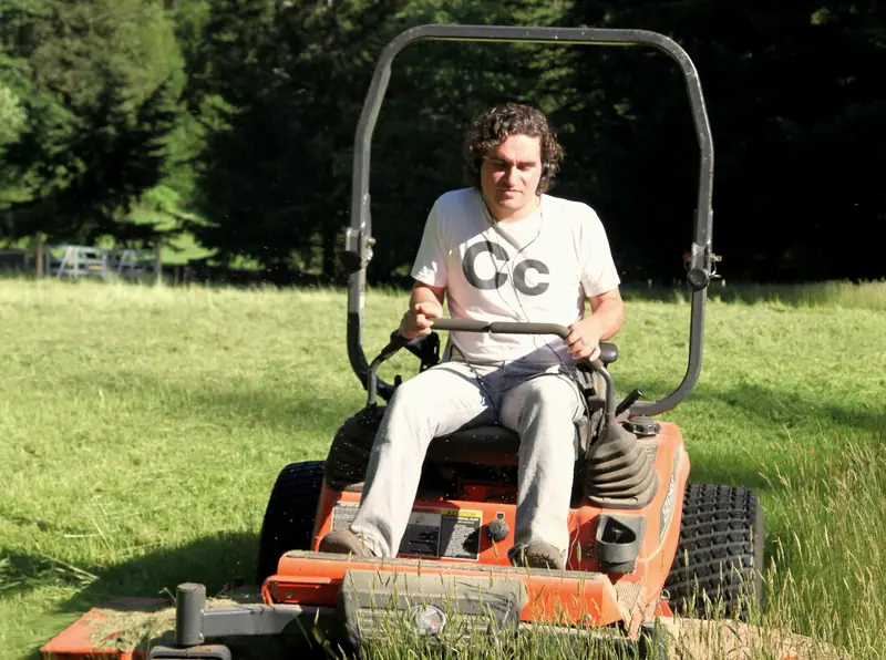 A landscaper mowing a lawn on a ride-on mower