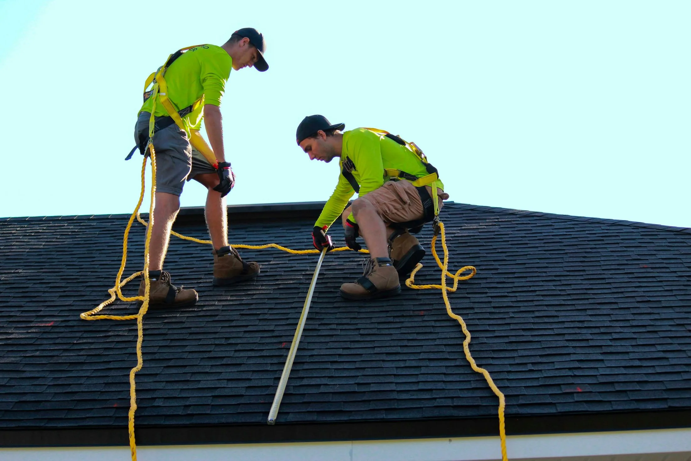 A roofing crew at work on a pitched roof under open sky